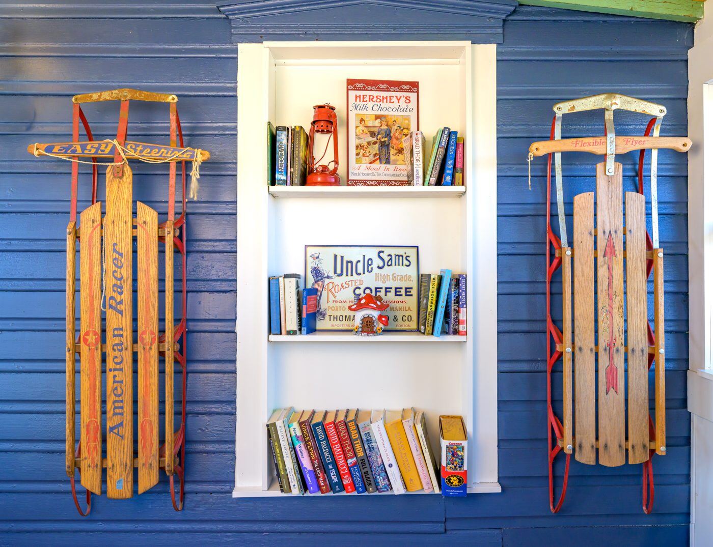 A styled bookshelf with colorful spines beside blue drapery at the Craven House